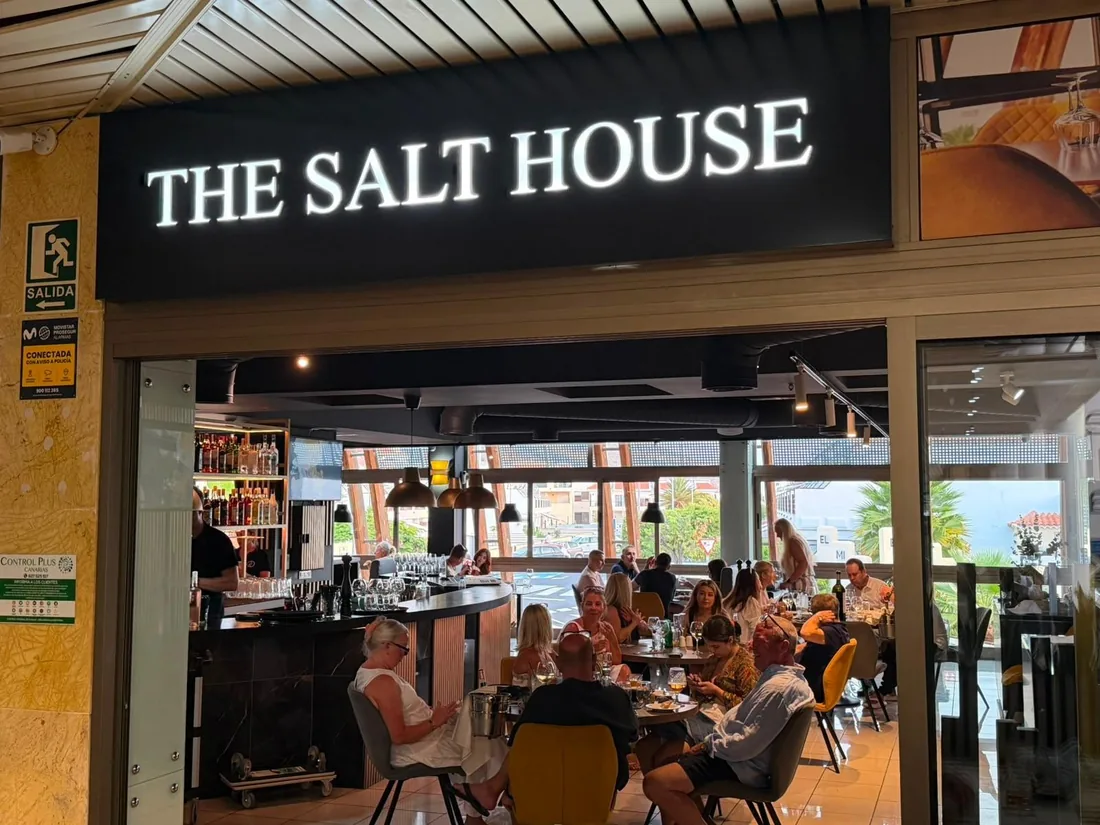 El r&oacute;tulo iluminado sobre la puerta, con clientes cenando dentro