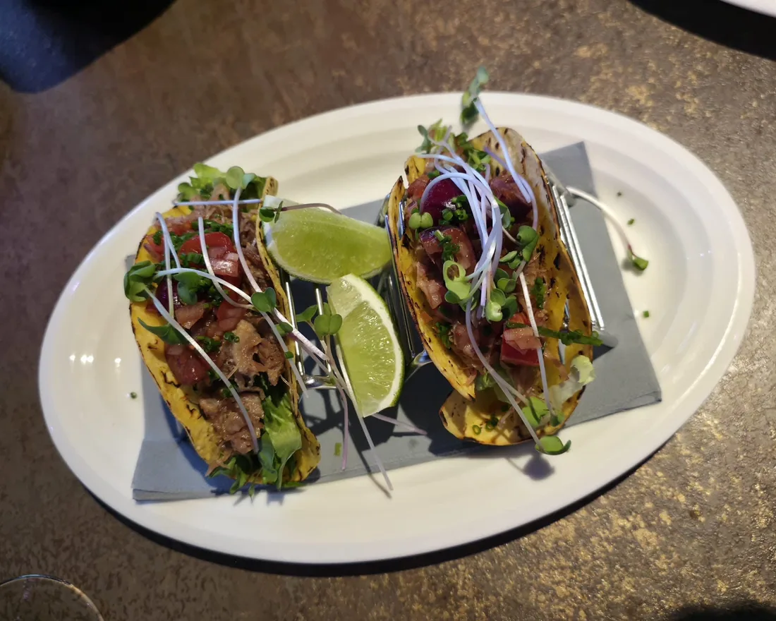 Two crispy duck tacos with lime and fresh herbs